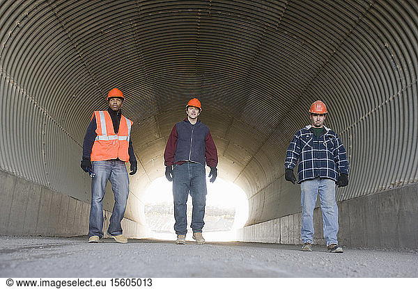 Three engineers walking in a tunnel at an asphalt plant