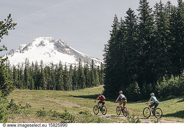 Three female friends mountain bike on a trail at Mt. Hood  Oregon.