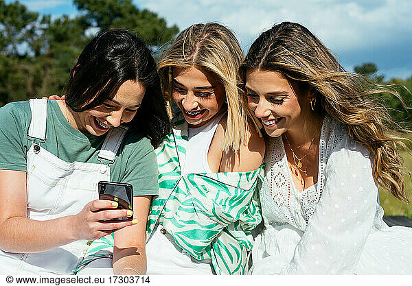 Three female friends using mobile phone and having fun