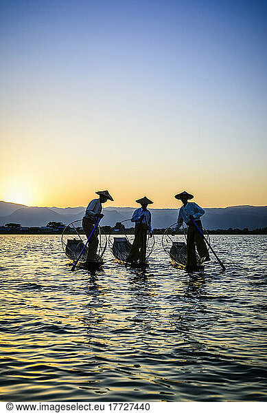 Three fishermen on Lake Inles  standing in their traditional boats.