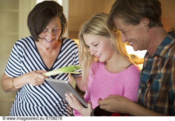 Three generation females searching recipe on digital tablet in kitchen