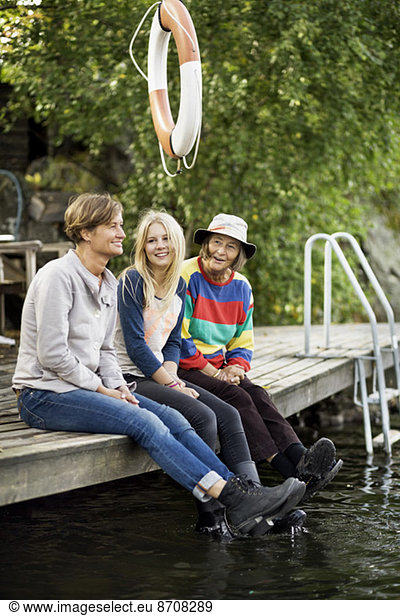 Three generation females sitting on pier