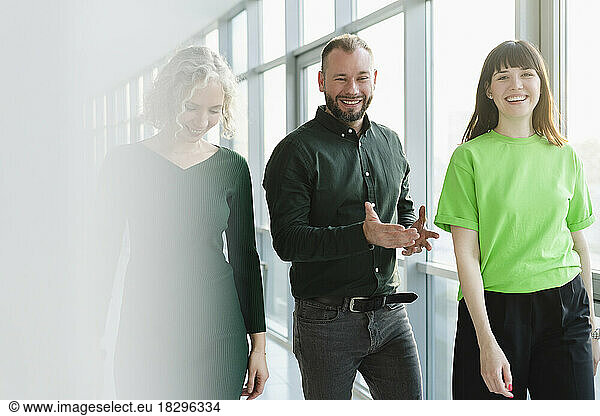 Three happy business people in green clothing on office floor