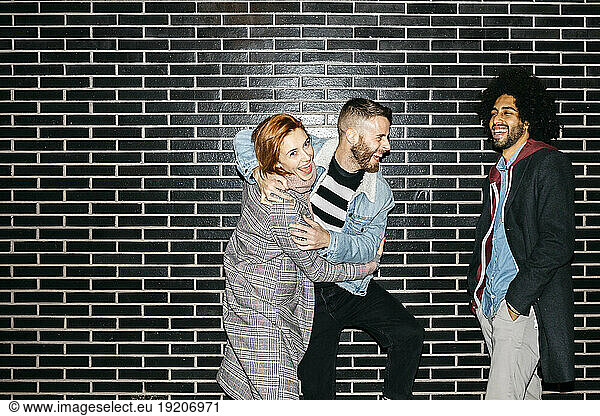 Three happy playful friends at a black wall