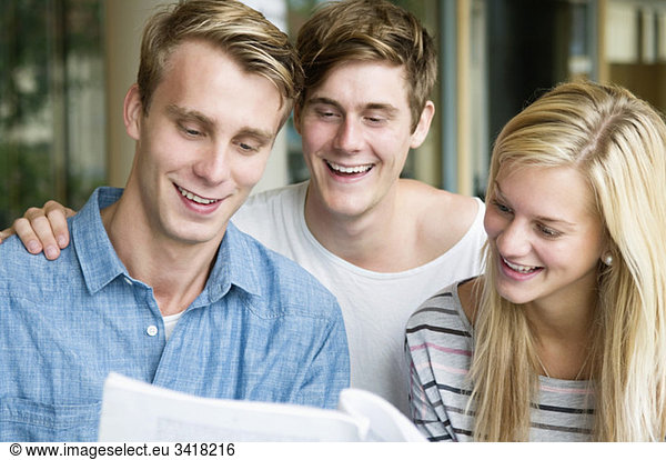 Three happy students reading booklet