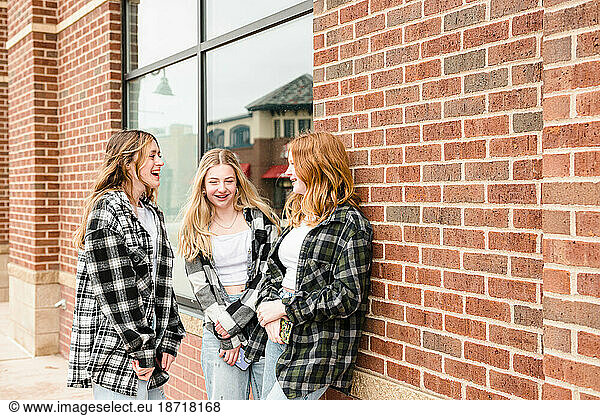 Three happy teen girls standing outside talking.