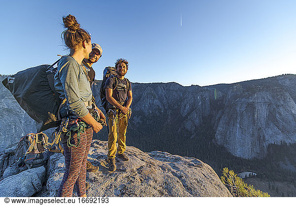 Three hikers at the top of El Capitan in Yosemite Valley at sunset