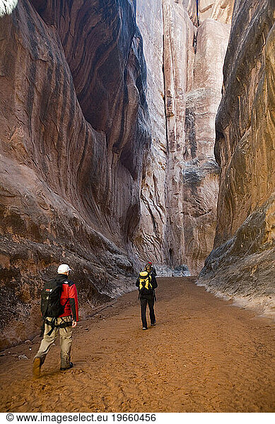 Three hikers in canyon  Arches National Park  Moab  Utah.