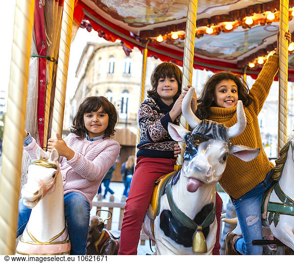 Three little children having fun on a carousel