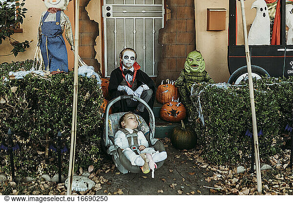 Three male siblings dressed in Halloween costumes posing at home