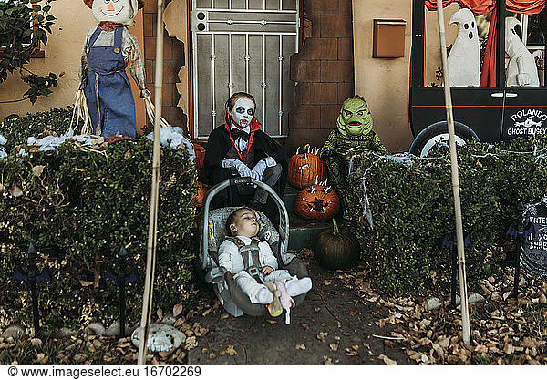 Three male siblings dressed in Halloween costumes posing at home