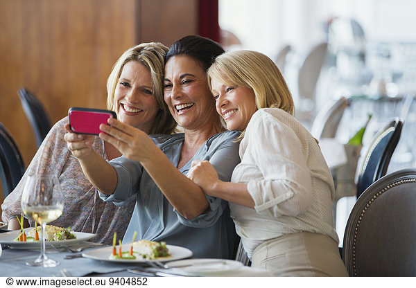 Three mature women taking selfie in restaurant