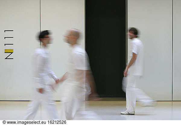 three men in white chlothes passing eachother
