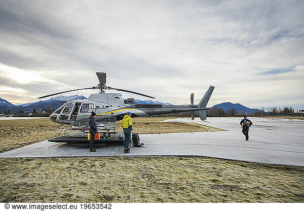 Three men prepare gear for flight in helicopter