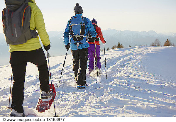 Three mid adult friends snowshoeing in Dolomite mountains  Eisack Valley  South Tyrol  Italy