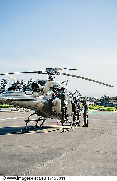 Three military men cleaning a helicopter in the sunlight
