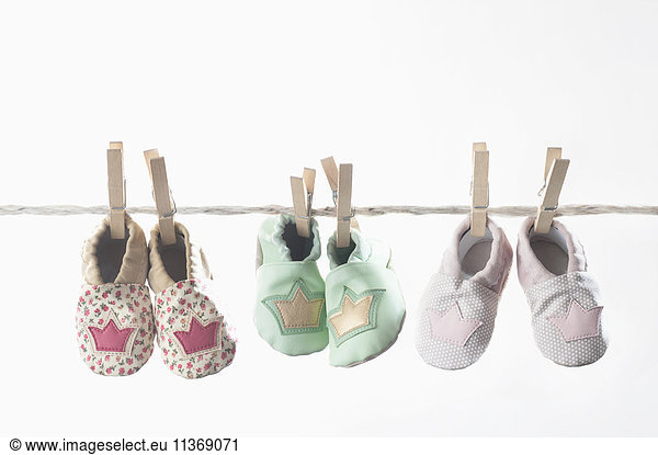 Three pairs of baby shoes hanging on clothes line