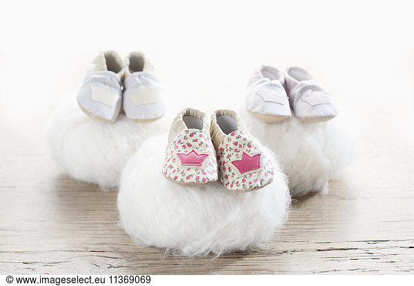 Three pairs of baby shoes on woolen soft balls