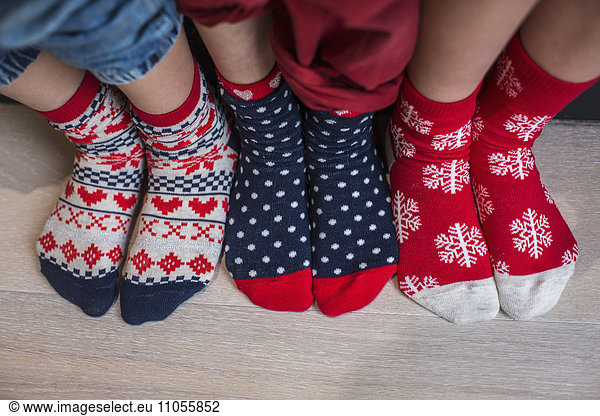Three pairs of children's feet in bright patterned Christmas socks.
