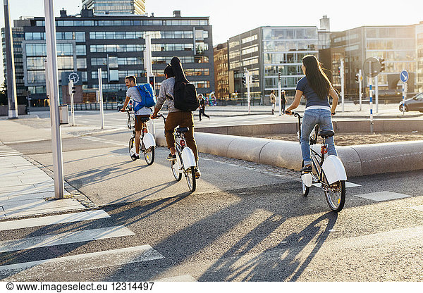 Three people cycling on city street
