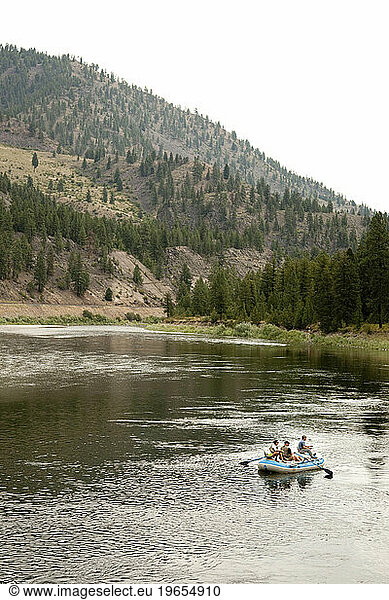 Three people fly fishing from a drift boat.
