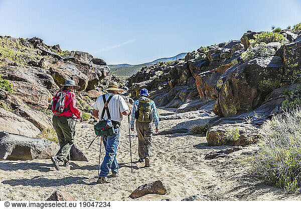 Three people walking on sand in Little Petroglyph Canyon  Ridgecrest  California  USA