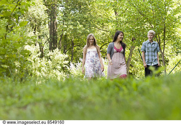 Three people  woman and children walking through woodland.
