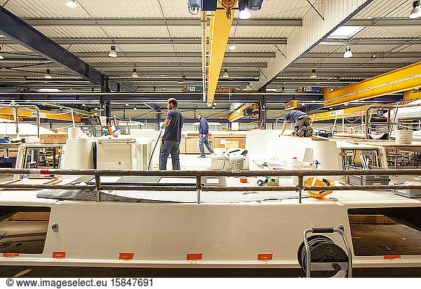 Three shipwrighters working on a top deck area of a multihull