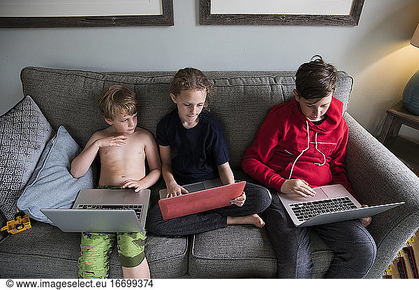 Three Siblings Work on Laptops Together Doing Virtual Learning