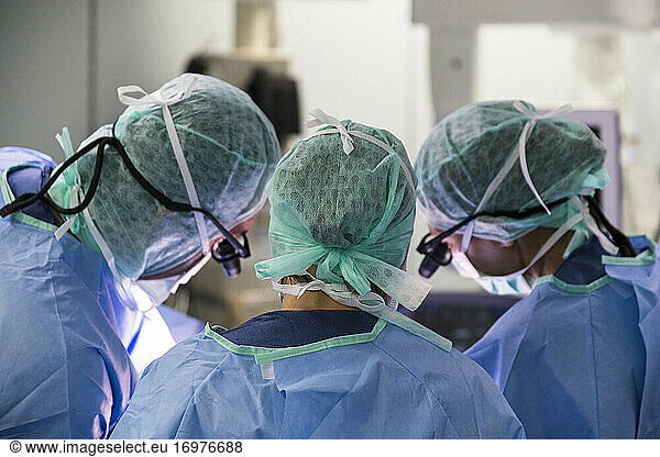 three surgeons  look at the operating field