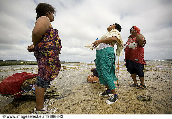 Three women laugh while waiting for the tide to fully recede off the reef.