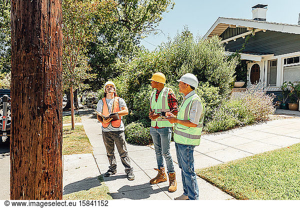 Three Workers Examine Telephone Pole