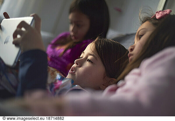 Three young Asian girls on the sofa playing with their tablet at home