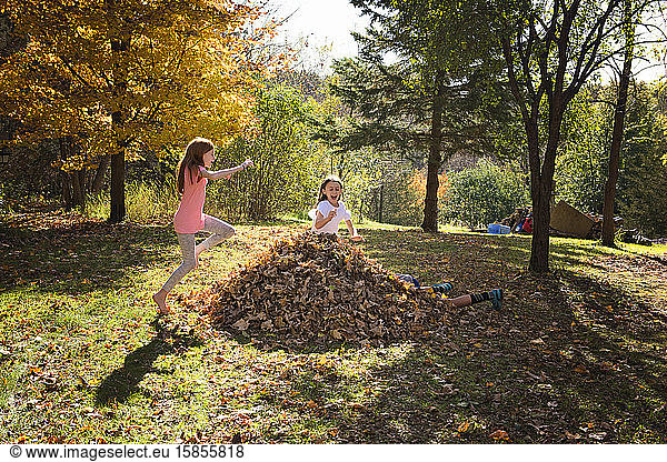 Three Young Friends Playing Outdoors in Fall Leaves