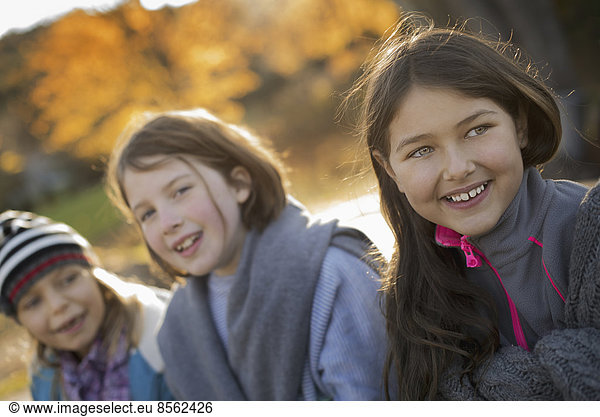 Three young girls  children  outside in the fresh air. Autumn foliage.