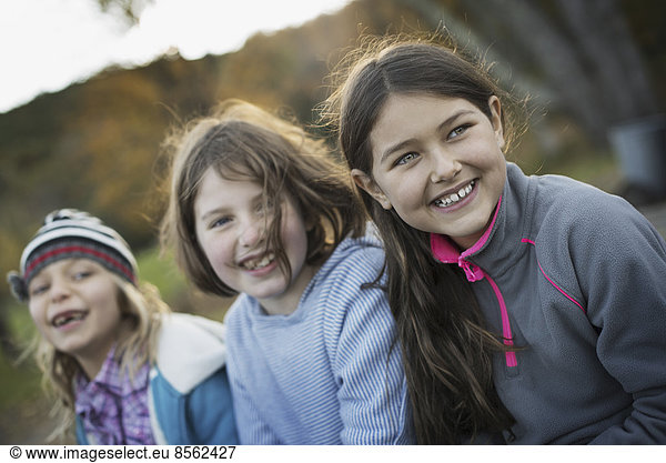 Three young girls  children  outside in the fresh air. Autumn foliage.
