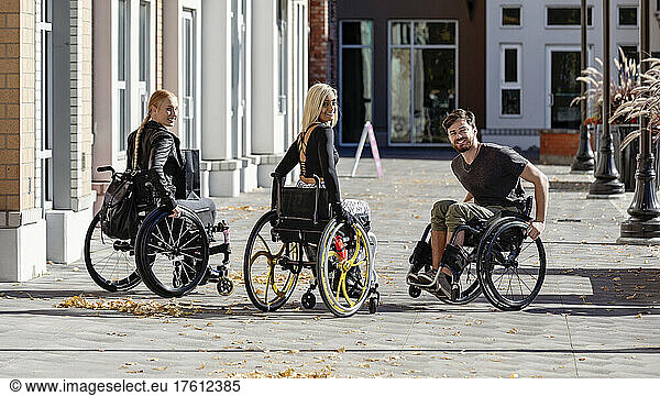 Three young paraplegic friends pose for the camera as they spend time together outside on a walkway in a city area; Edmonton  Alberta  Canada