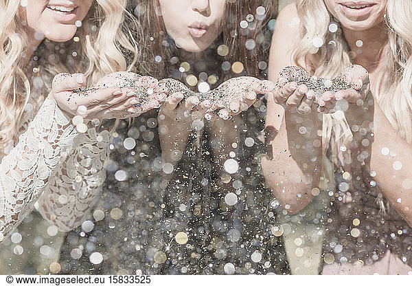 Three young women blow glitter in college graduation celebration