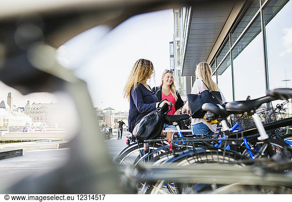 Three young women standing by bicycles