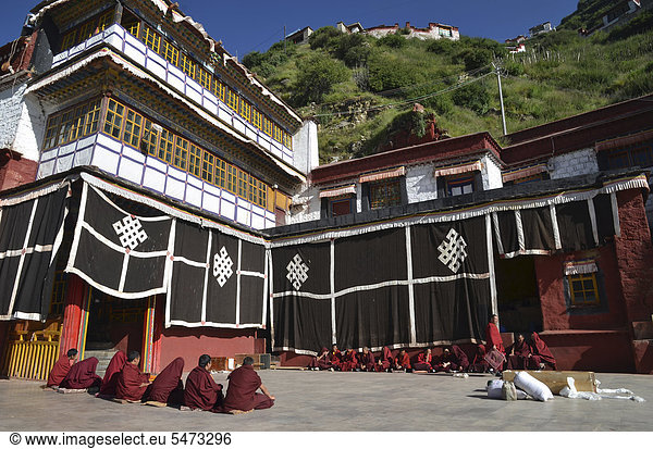 Tibetischer Buddhismus  tibetische Mönche in roter Robe sitzen bei einer Zeremonie zur Vorbereitung für das Himmelsbegräbnis eines Leichnams welcher in einer Holztrage gebettet ist  Klosteranlage Kloster Drigung  Drigung Til  Bezirk Lhundrup  Zentraltibet  Himalaya  Tibet  China  Asien