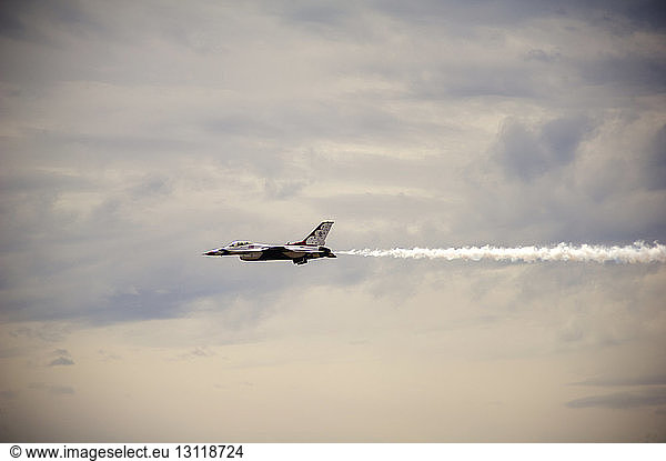 Tiefblick auf Kampfflugzeug  das bei bewölktem Himmel fliegt