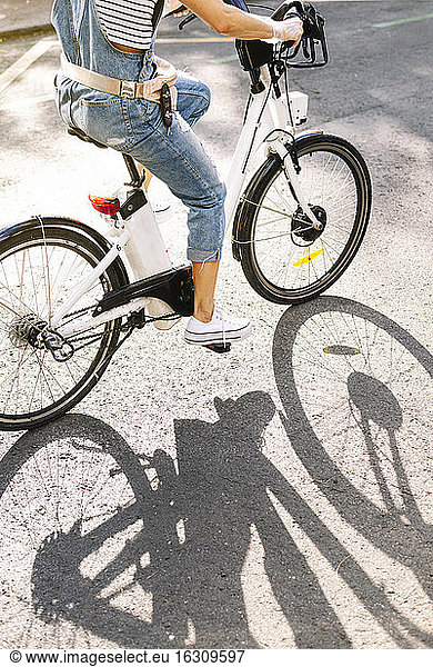 Tiefschnitt einer Frau  die an einem sonnigen Tag auf der Straße Fahrrad fährt