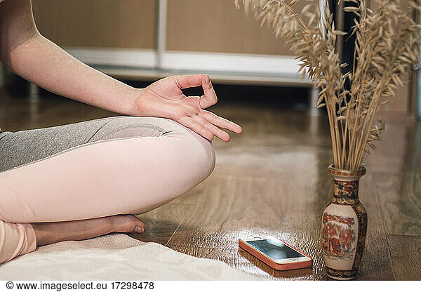 Tiefschnitt einer Frau  die zu Hause Yoga im Lotussitz macht