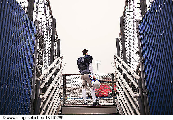 Tiefwinkelansicht eines American-Football-Spielers  der im Stadion gegen den Himmel steht