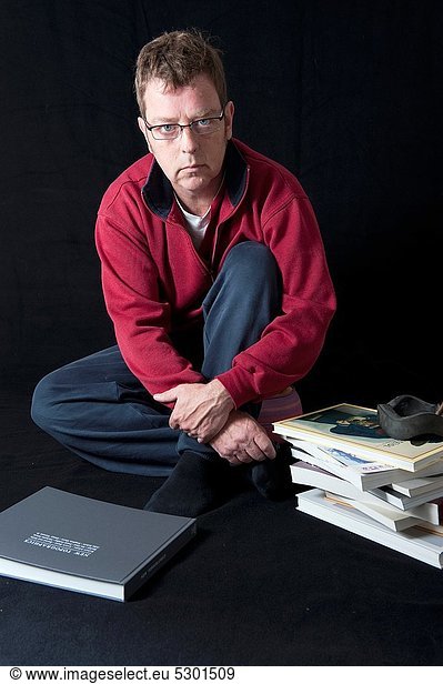 Tilburg  Netherlands. Self-portrait of a male photographer  with photo-books in his studio on a relaxed Sunday morning.