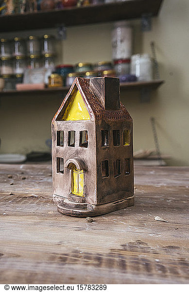 Tiny ceramic house on workbench in a pottery