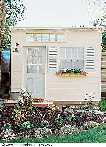 Tiny shed with blue door  shutters  and garden