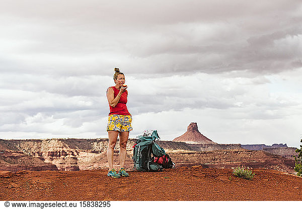 tired female hiker eats apple during a long day backpacking in desert