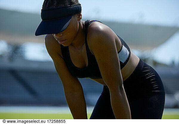 Tired female track and field athlete in visor resting