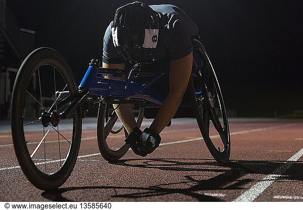 Tired paraplegic athlete resting on sports track after wheelchair race at night